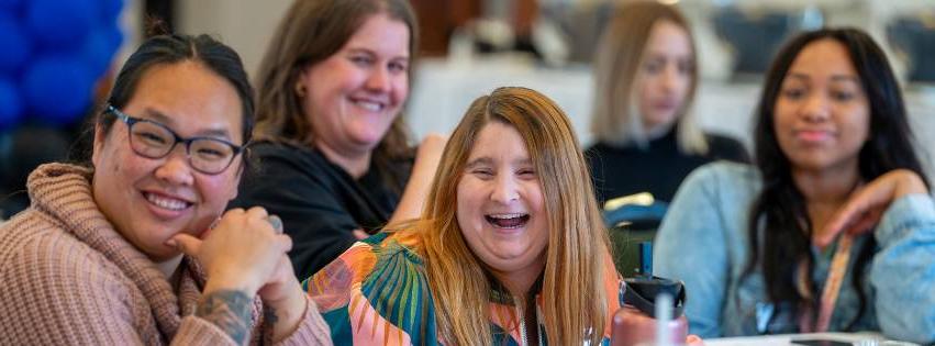 Image of people laughing at an event on campus. Main focus is a women laughing in the middle.